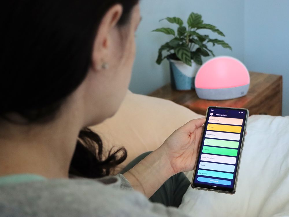 A woman using the Hatch Restore app to program her bedtime and wake settings.