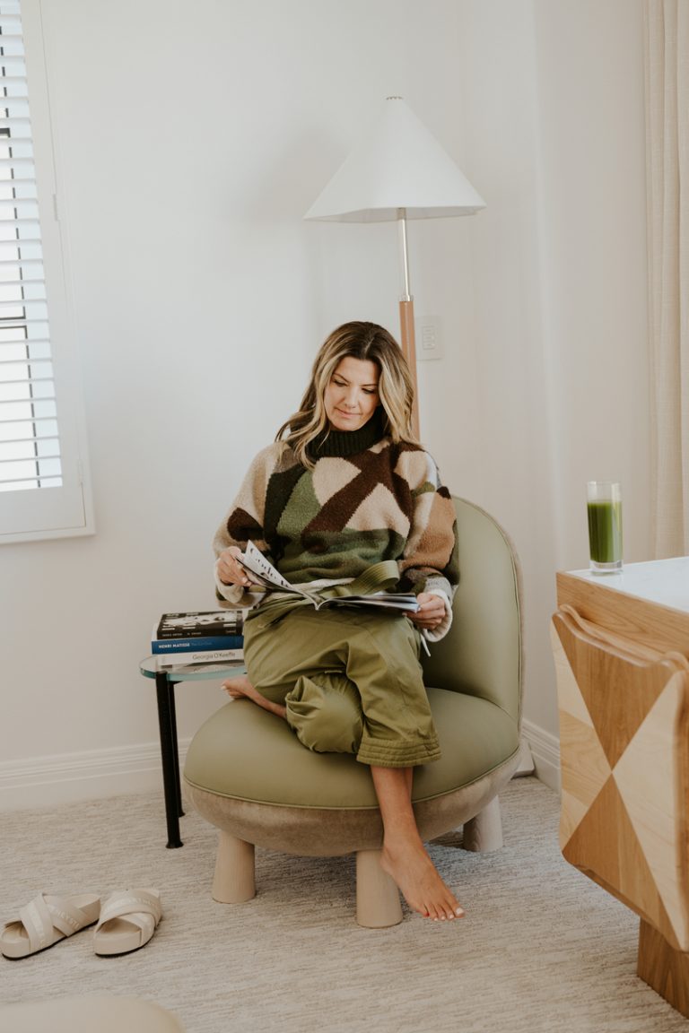 Frau liest auf Stuhl mit grünem Smoothie