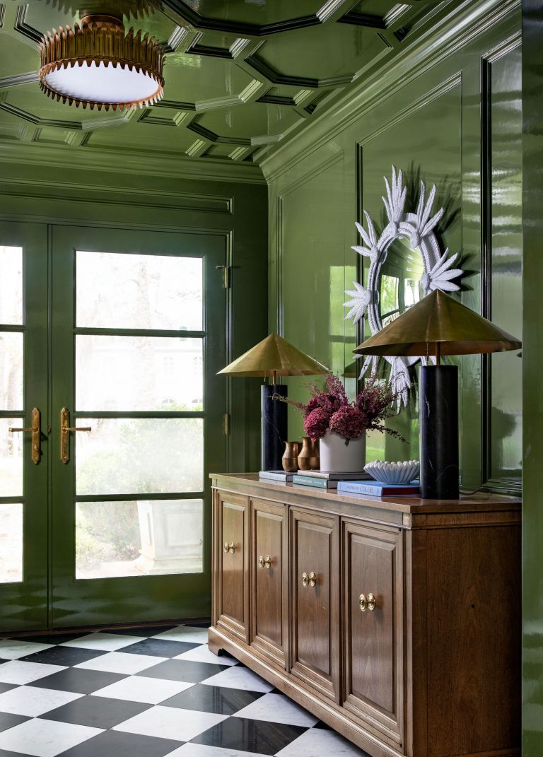 Tiefgrünes Zimmer mit französischen Türen, schwarz-weiß kariertem Boden und Buffettruhe aus Holz.
