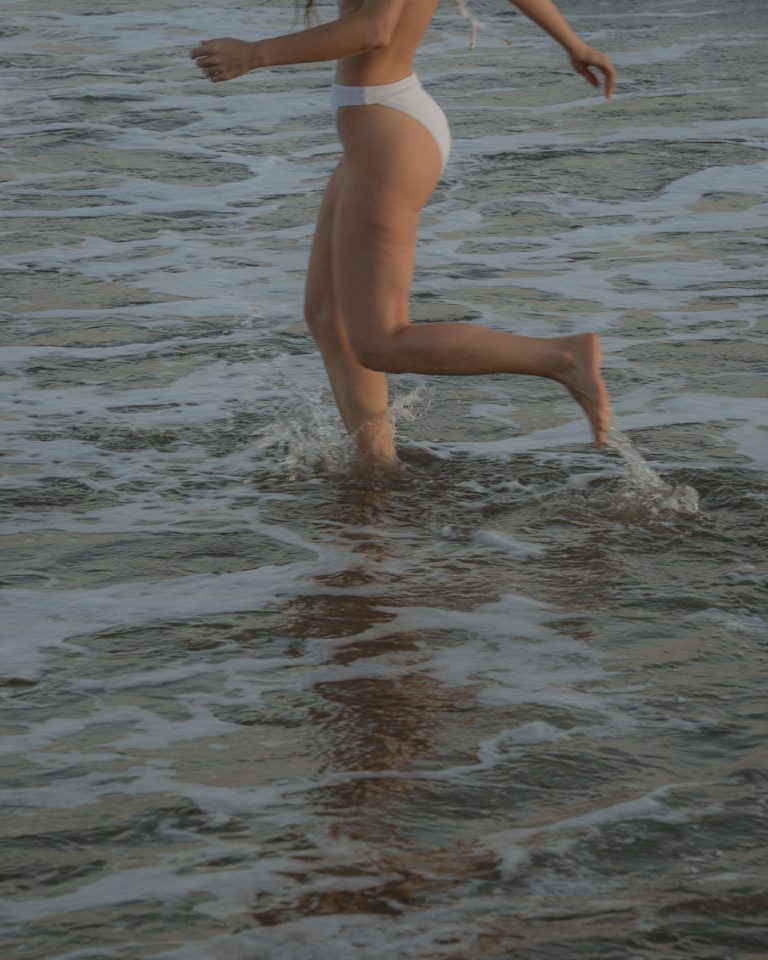 Frau springt im Badeanzug im Ozean.